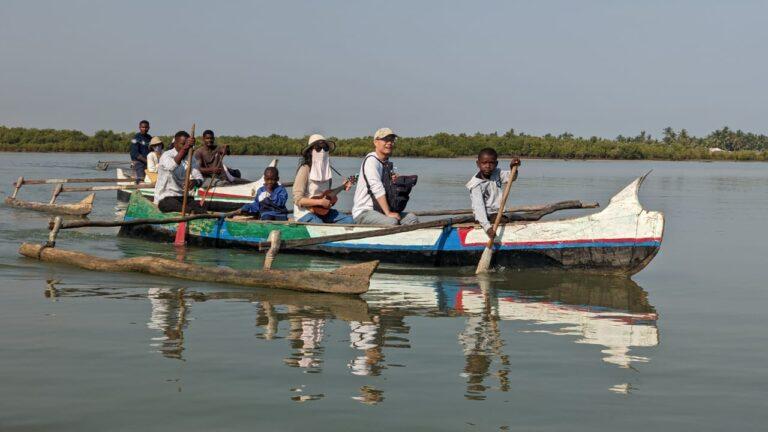 Voyageurs en pirogue avec des habitants à Madagascar lors d’un séjour chez l’habitant sur une rivière entourée de nature tropicale.